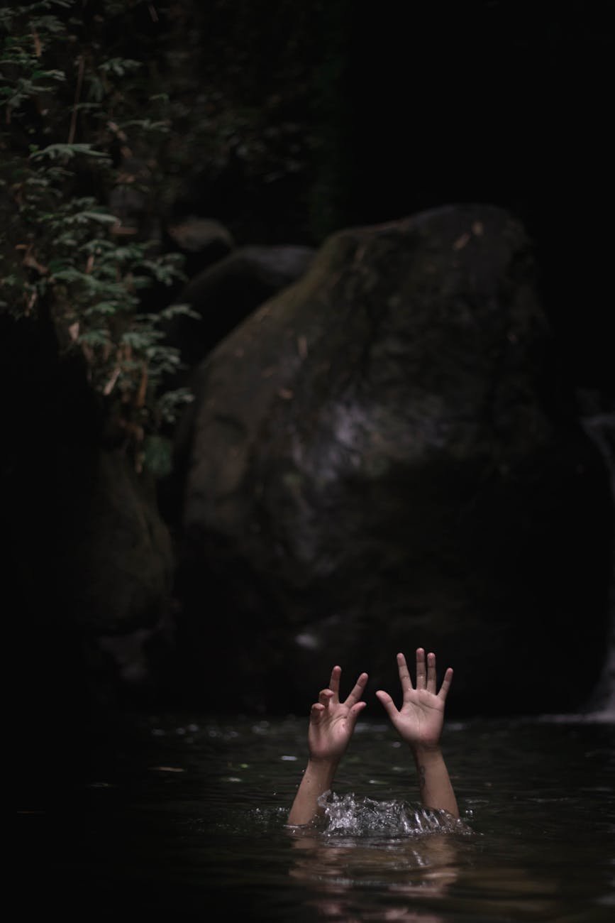 person underwater with hands up on air